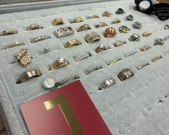 Ring-Display mit Gold- und Silberringen, Juwelier-Lupe und JASPERS-Karte bei der Bewertung