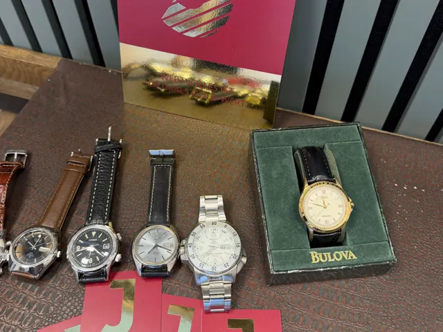 Fünf Armbanduhren und Bulova-Uhrenbox vor dem JASPERS-Aufsteller